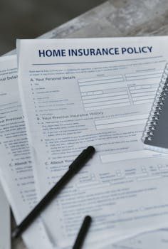 Insurance policy documents and a magnifying glass on a wooden table next to a coin collection