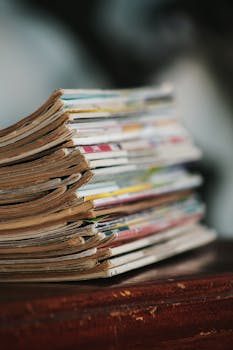 a stack of various collector magazines neatly piled on a wooden table