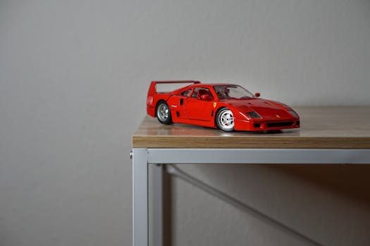 Close up of a red 1:18 scale Ferrari diecast model on a white shelf with hood open showing detailed engine