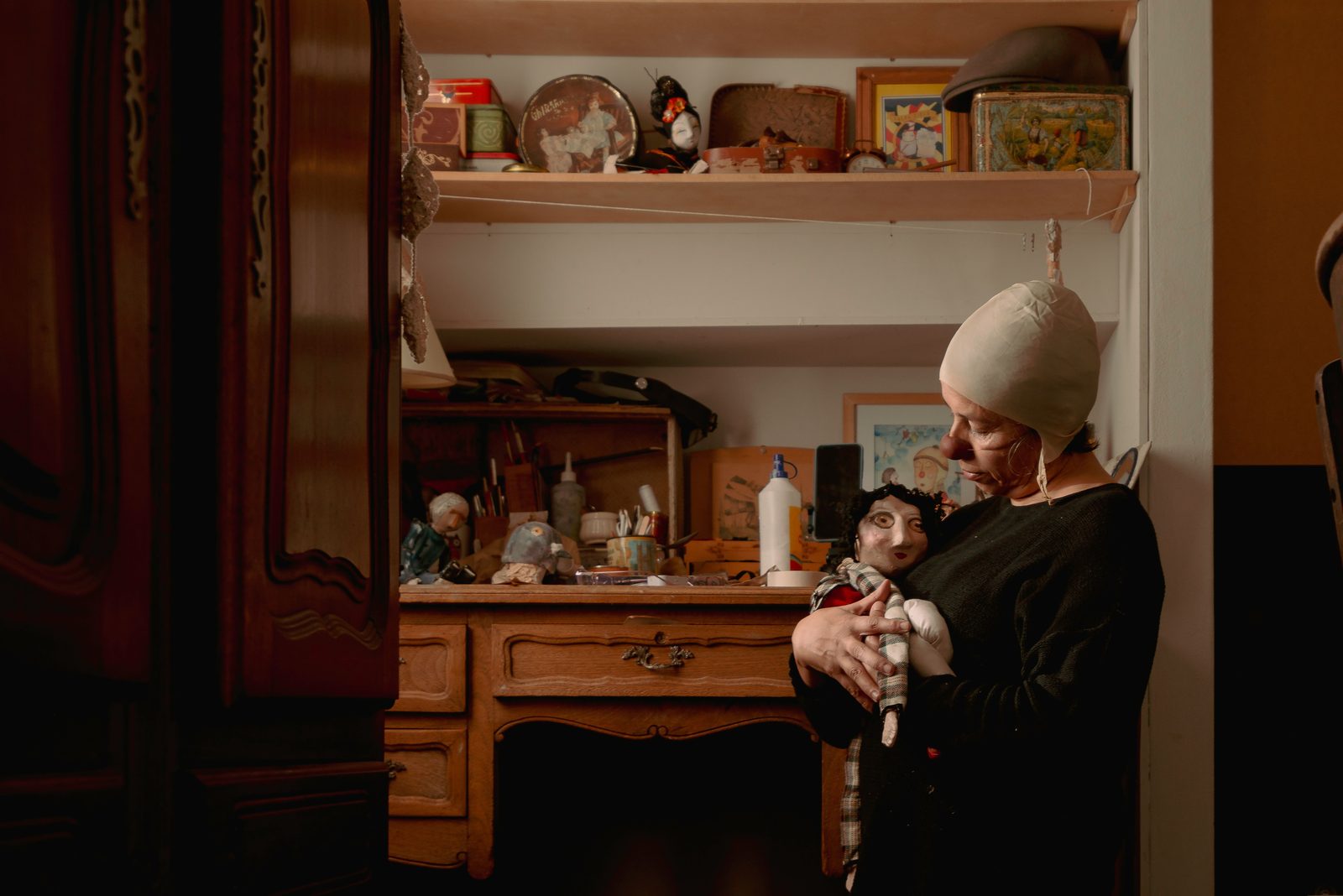An artisan lovingly holds a puppet in a warm, vintage workspace filled with artistic materials.