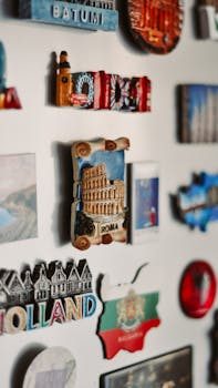 A shadow box filled with small travel souvenirs including coins and shells displayed on a wall