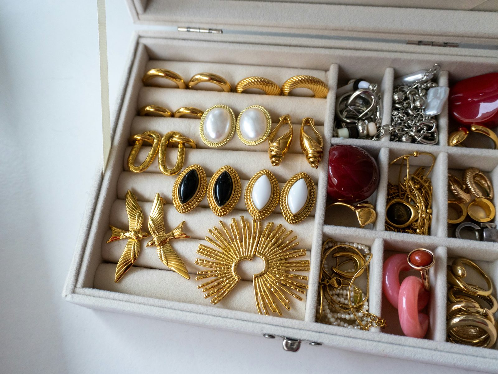 A jewelry box filled with assorted gold and pearl earrings