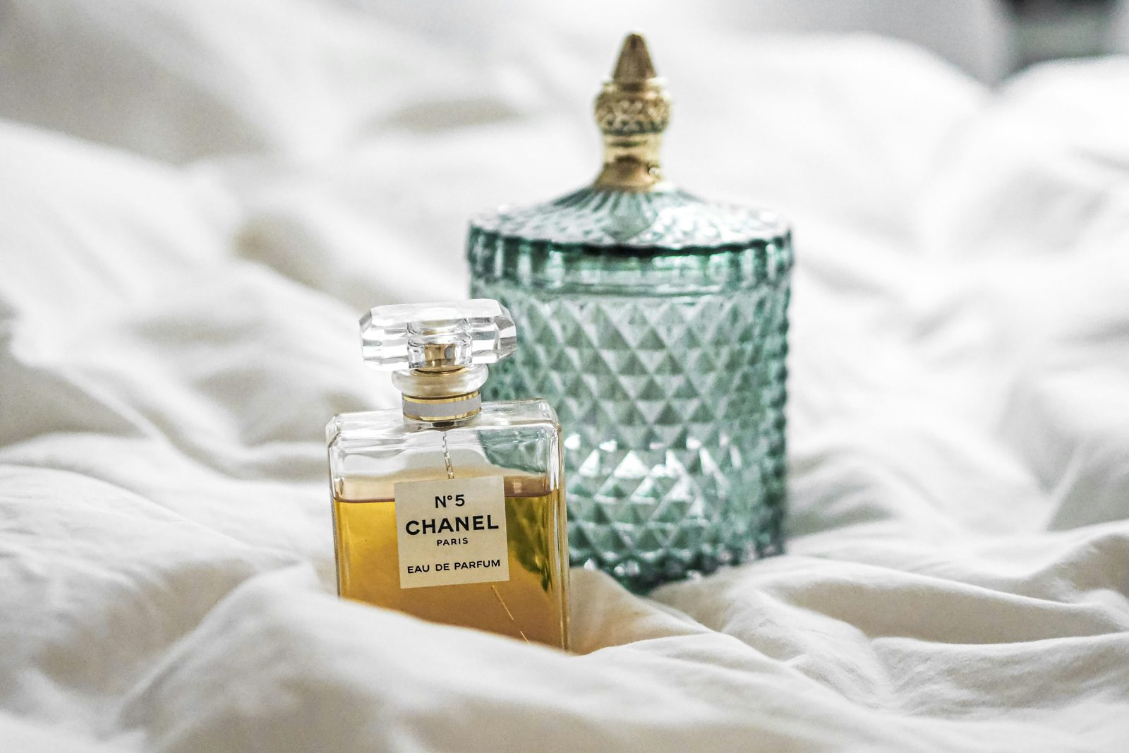 a bottle of perfume sitting on top of a bed