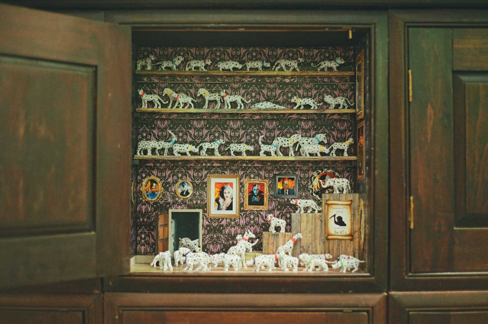 A wooden cabinet displays white animal figurines and framed pictures