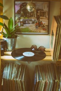 A stack of vinyl records on a shelf next to a turntable in a cozy room